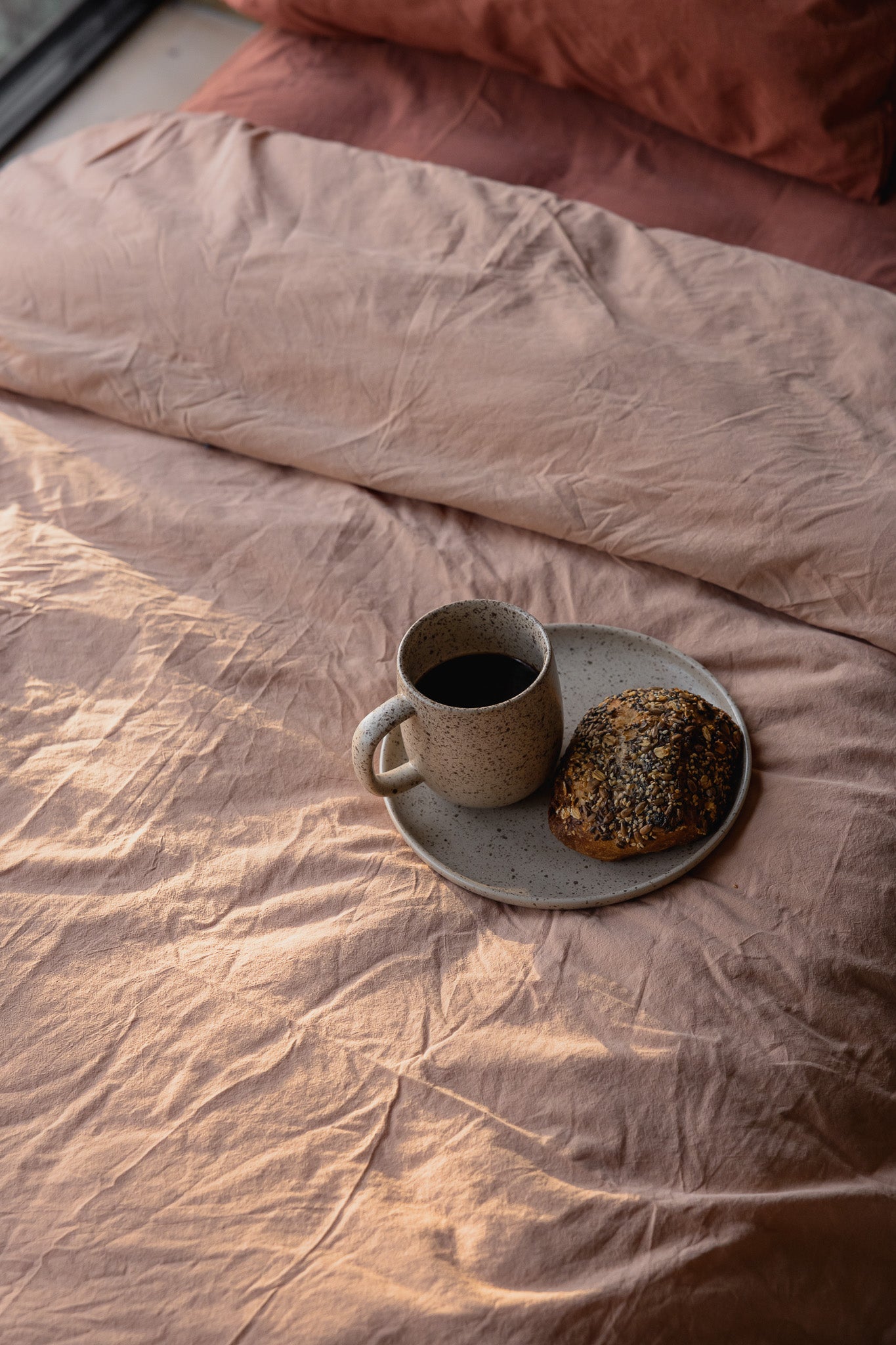 Påslakanset Crinkle Peach Pink – sängkläder bredvid en kopp och ett bakverk
