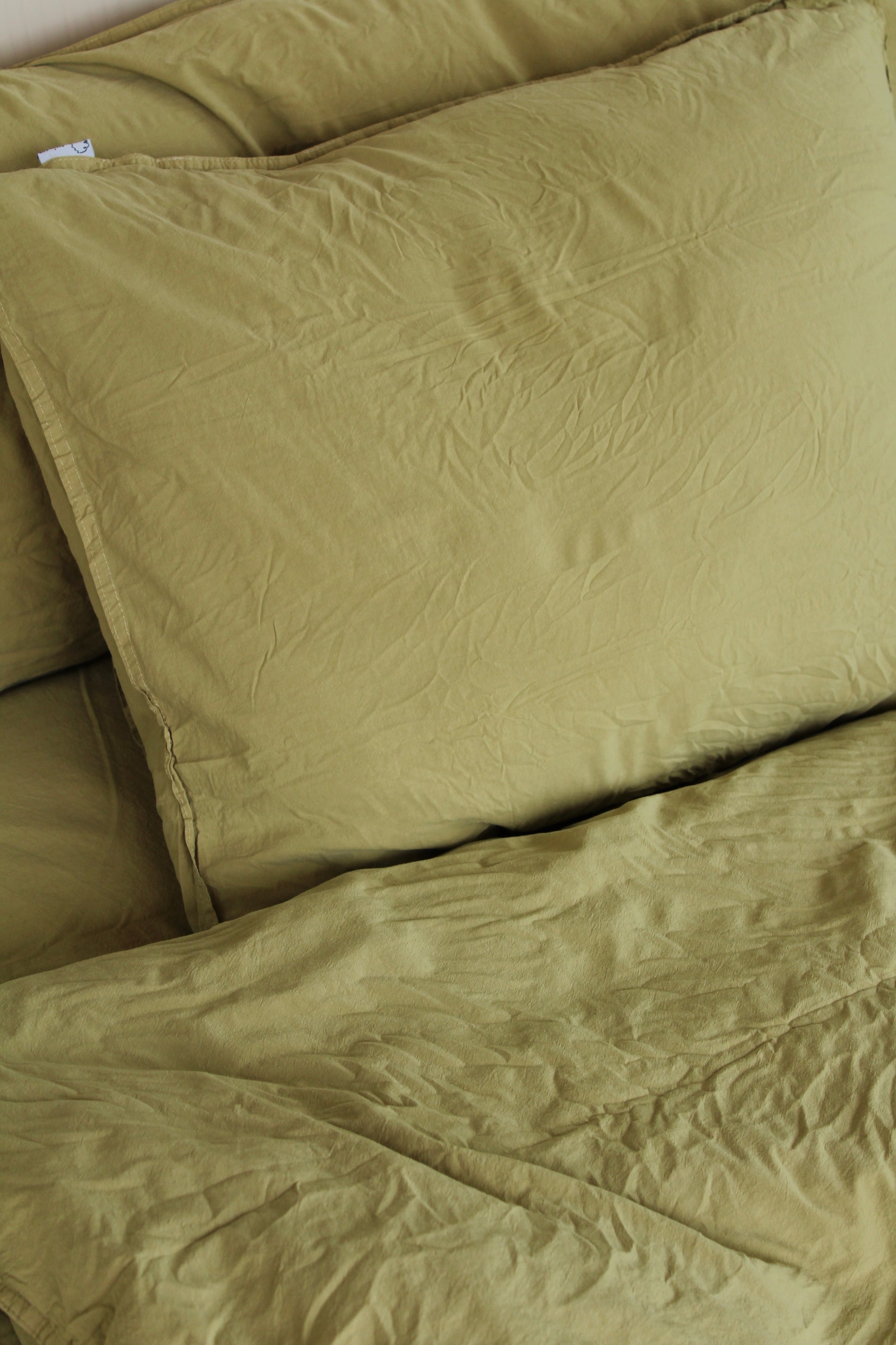 Kuddfodral Crinkle Khaki green – närbild av kudde på säng