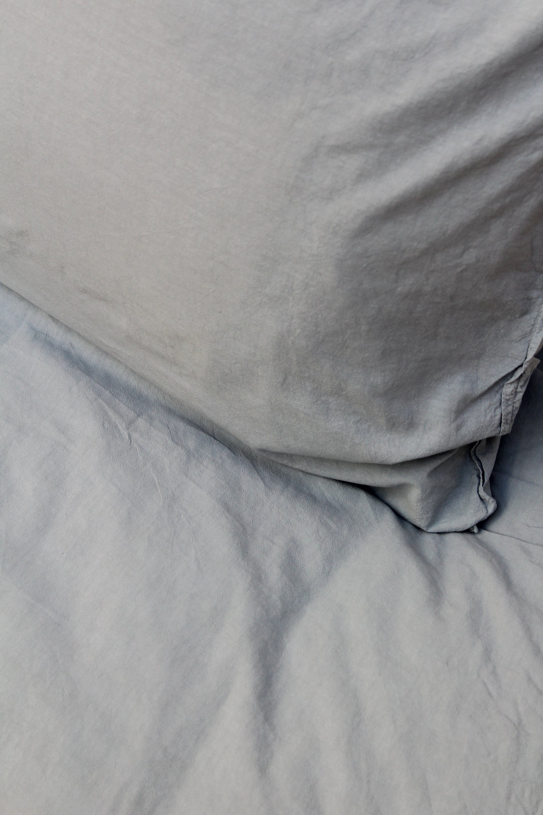 Kuddfodral Crinkle Mist Blue – närbild av kudde på säng