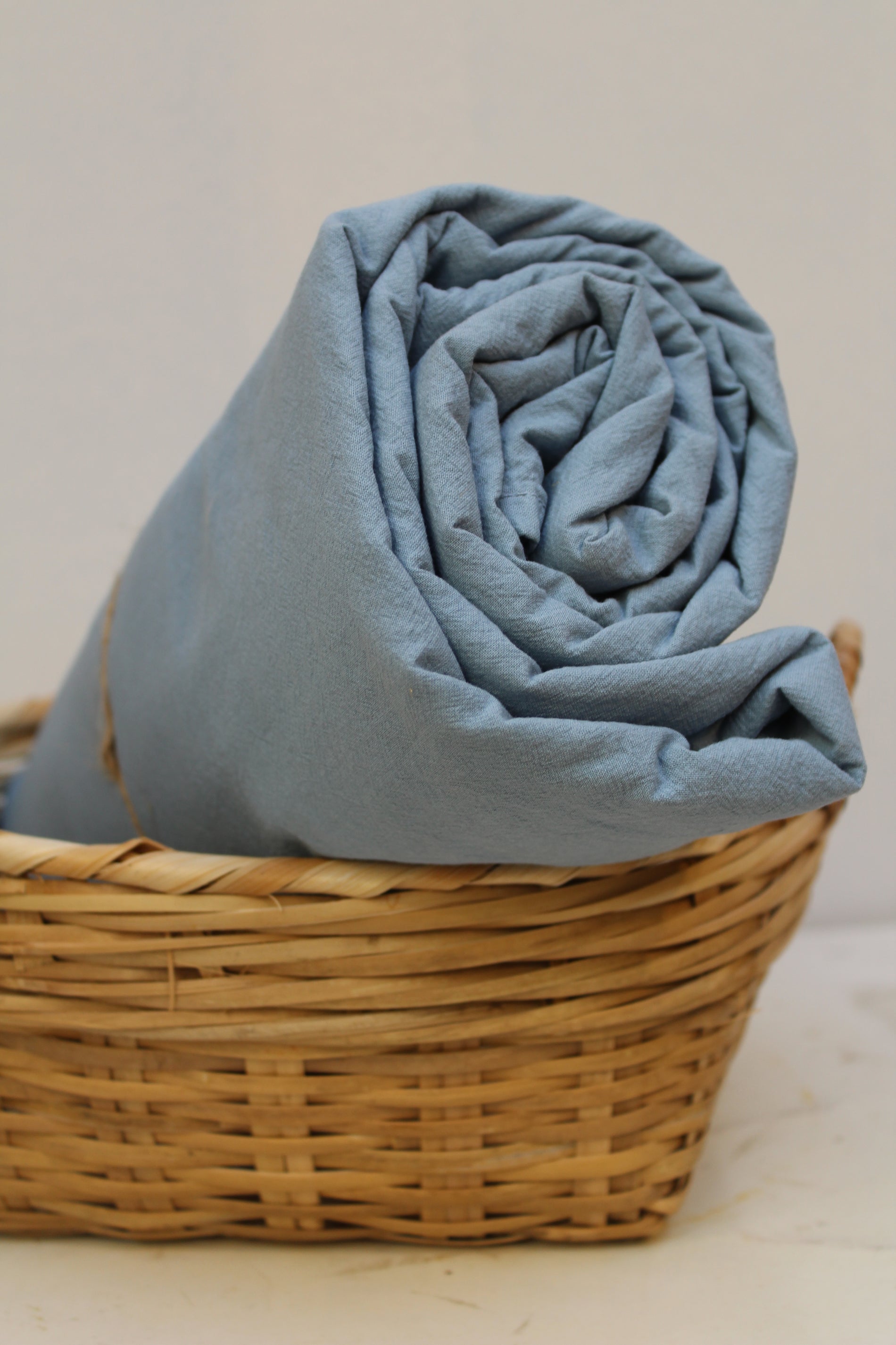 Lakan Crinkle Mist Blue – ihoprullat i en flätad korg