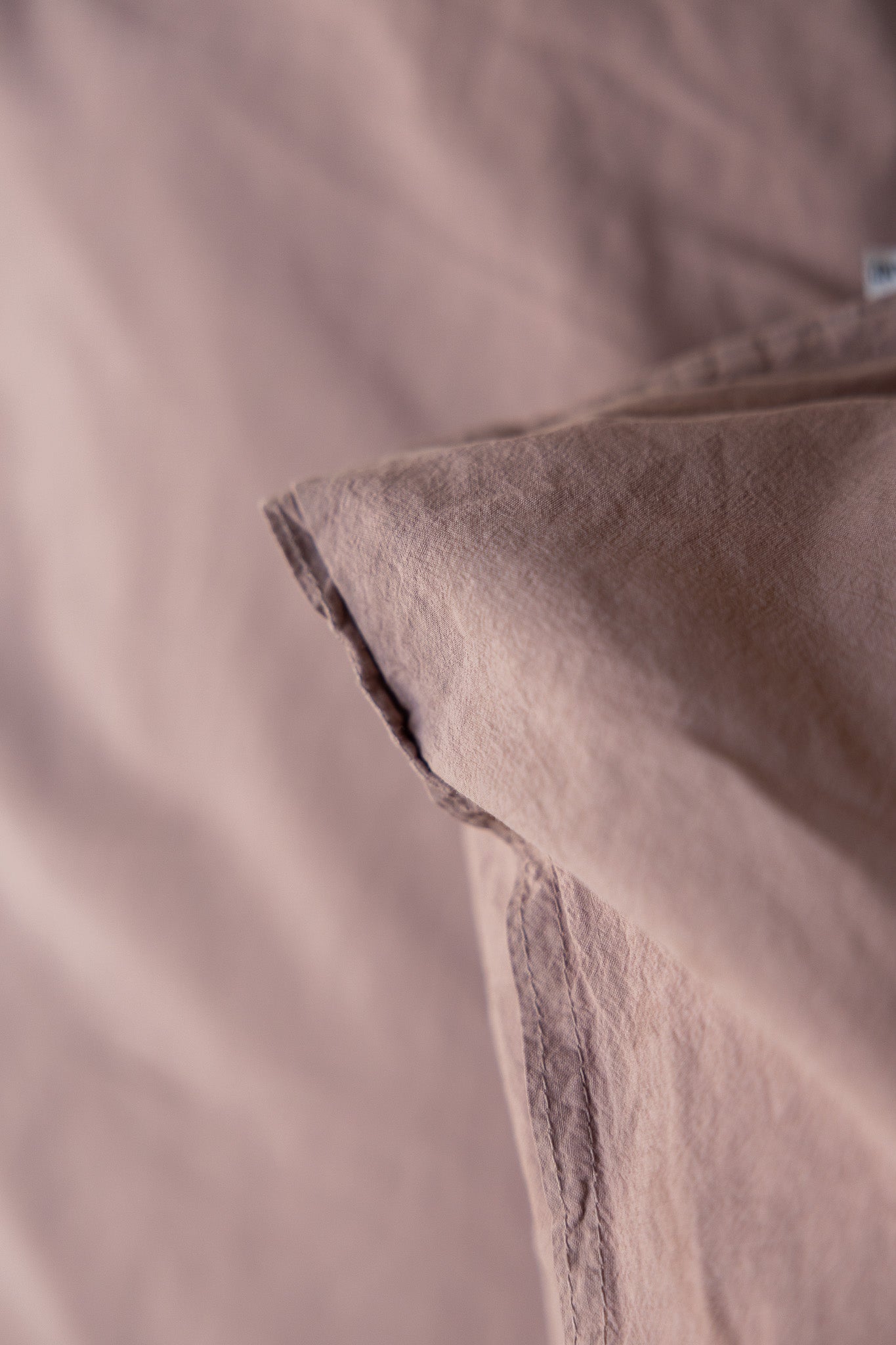 Kuddfodral Crinkle Rose Taupe – närbild av kudde på säng